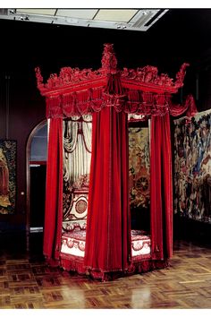 an ornate canopy bed with red drapes and curtains