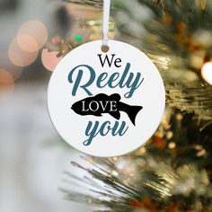 a white ornament hanging from a christmas tree with the words we reely love you