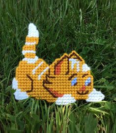 a crocheted cat laying in the grass