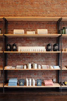 shelves with books, teapots and other items in front of a brick wall