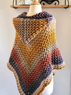 a multicolored crocheted shawl hanging on a mannequin head