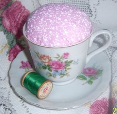 a tea cup and saucer with a spool of thread