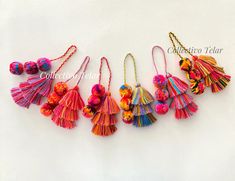 five tasselled key chains with pom poms hanging from them