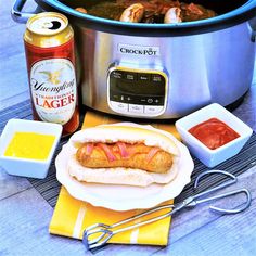 a hot dog sitting on top of a white plate next to an open crock pot