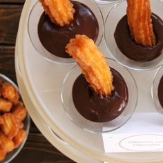 chocolate desserts are arranged in glass cups on a tray with dipping sauce and fried onion rings