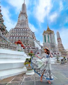 a woman standing in front of a building with many spires on it's sides