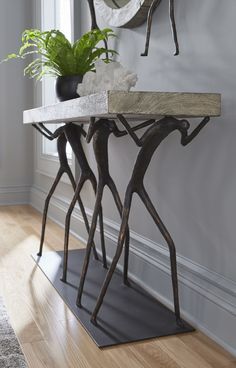 a table with some plants on top of it and a clock hanging above the table