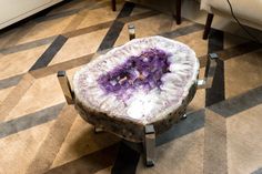 a purple and white rock sitting on top of a metal stand in a living room