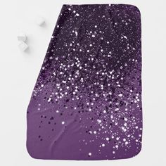 purple and white paint splattered on the surface of a blanket with cubes next to it