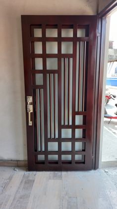 an open wooden door on the side of a building with glass panels and wood flooring