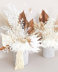 two vases with dried flowers in them on a table