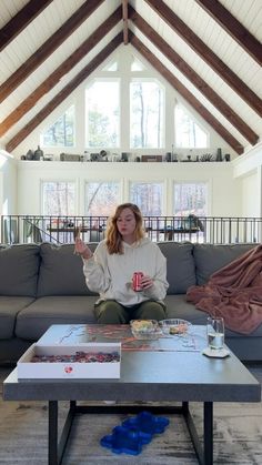 a woman sitting on top of a couch in a living room next to a coffee table