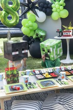 a table topped with lots of food and balloons in the shape of blocks on top of it