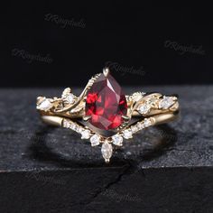 a gold ring with a red stone surrounded by white diamonds