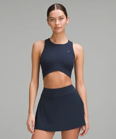 a woman wearing a black tennis skirt and top with cutouts on the sides,