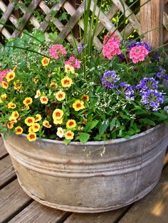 a bucket full of flowers sitting on top of a wooden table