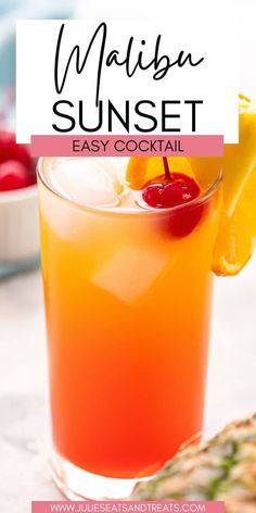 a close up of a drink in a glass on a table with fruit and pineapples