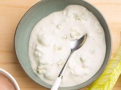 a bowl of yogurt with a spoon in it next to two bowls of dip