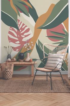 a chair and table in front of a wall with large leaves painted on the walls