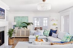 a living room filled with furniture and a fire place under a chandelier in front of a fireplace