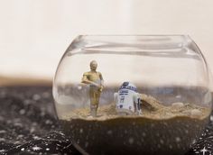 a star wars scene in a fish bowl with two figurines on the table