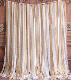 a gold and white curtain hanging from the side of a wall