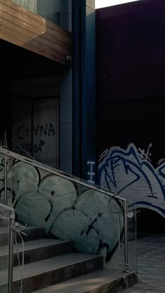 graffiti on the side of a building next to stairs and railings with handrails