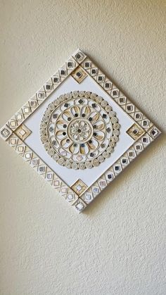 an intricately designed wall hanging on the side of a white wall with gold accents