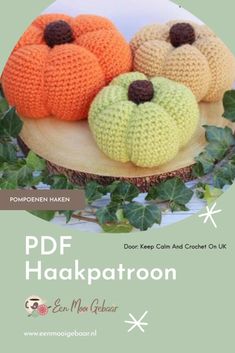 three knitted pumpkins sitting on top of a wooden board with leaves around them