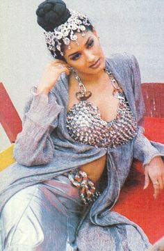 a woman sitting on top of a red bench wearing a silver dress and headpiece