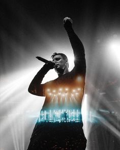 a man standing on top of a stage with his arms in the air and lights behind him