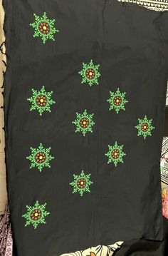 a black blanket with green and yellow designs on it, sitting on top of a table