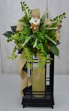 a vase filled with flowers and greenery on top of a table