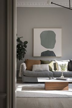 a living room filled with furniture and a painting hanging on the wall above it's head