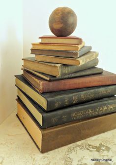 a stack of books sitting on top of each other next to a wooden apple statue