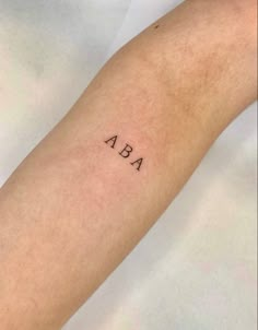 a person's arm with the word ab on it, and an arrow tattoo