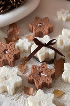 some chocolates are on a table with leaves and pine cones around them, as well as a brown ribbon