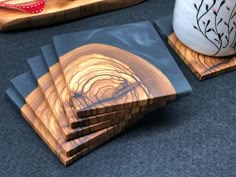 four wooden coasters sitting on top of a table next to a vase and bowl