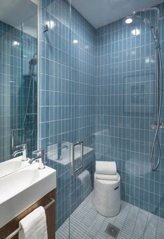 a blue tiled bathroom with a shower, sink and toilet