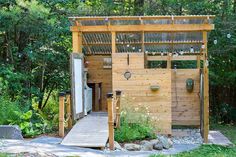 a small wooden structure in the middle of a forest with trees and bushes around it