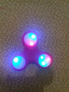 a pink and blue light up fidget sitting on top of a carpet