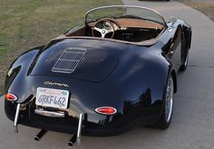 an old black sports car is parked on the side of the road next to a curb