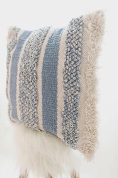 a blue and white striped pillow sitting on top of a wooden stand