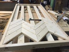 an unfinished bed frame being built in a workshop with tools on the floor and wood planks around it