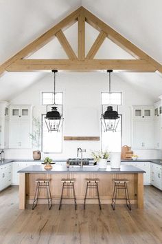 an open kitchen with white cabinets and wooden beams on the ceiling, along with stools