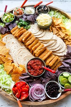 a platter filled with tortillas, salsa and other foodstuffs on a table