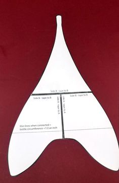 a cut out piece of paper sitting on top of a red table next to a cell phone