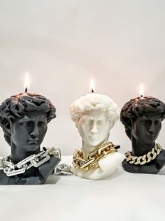 three candles that have faces on them with chains around them