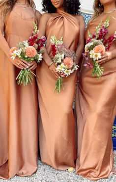 three bridesmaids in brown dresses posing for the camera with their bouquets on