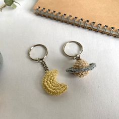 two crocheted key chains sitting on top of a table next to a plant